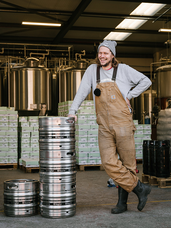 A man standing and leaning on beer kegs at Pilot Brewery