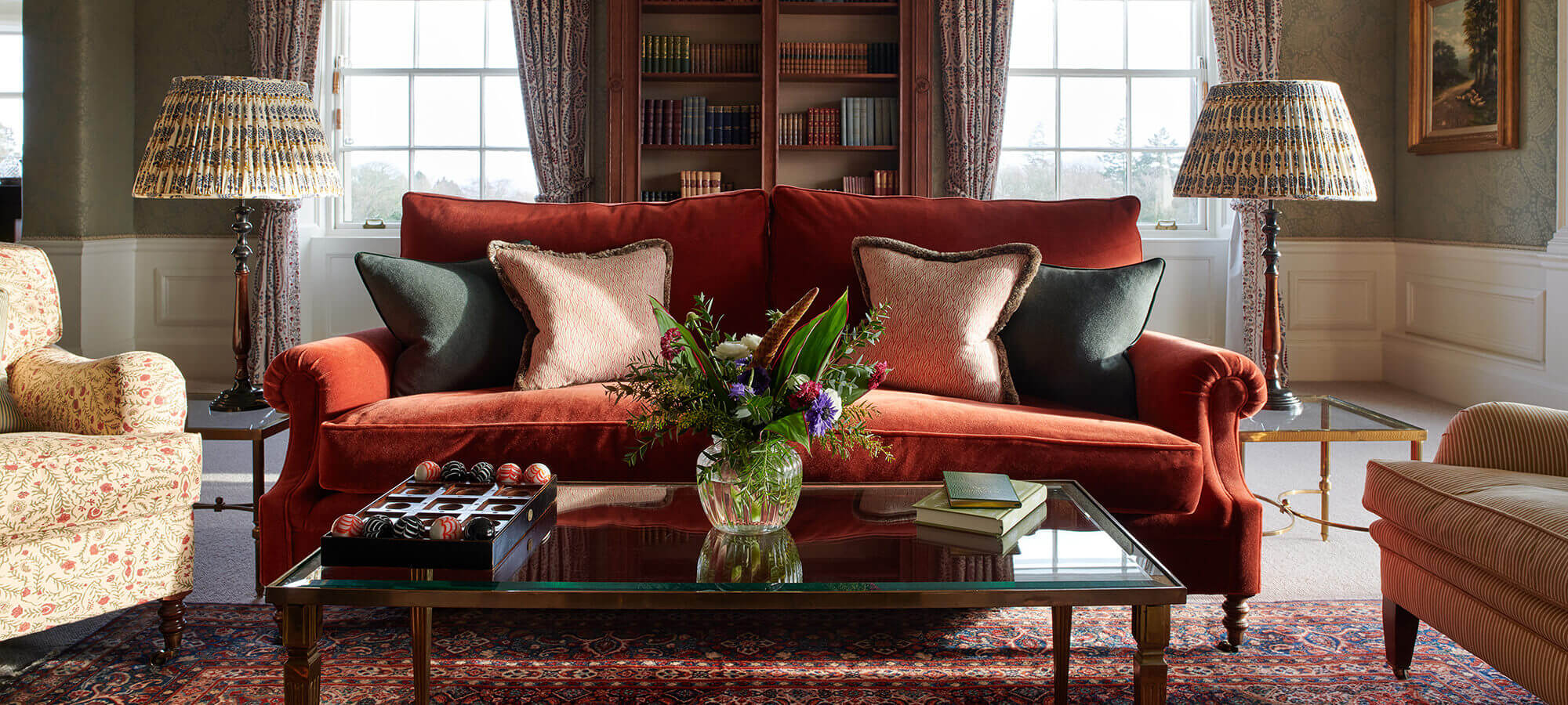 A large red velvet sofa sits behind a glass table with book and flower arrangement in the Royal Lochnagar Suite