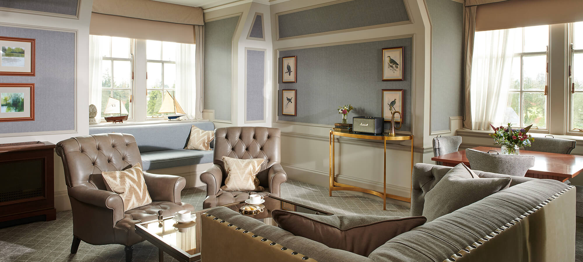 A large sitting room in a suite with two grey leather Chesterfield chairs in an estate suite