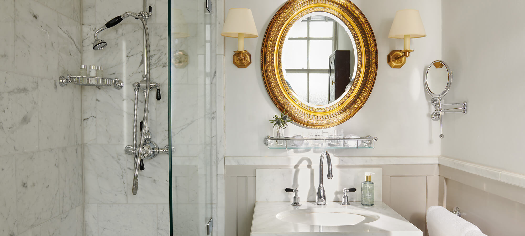 Un grand miroir doré au-dessus d'un lavabo en porcelaine blanche dans une chambre Country.