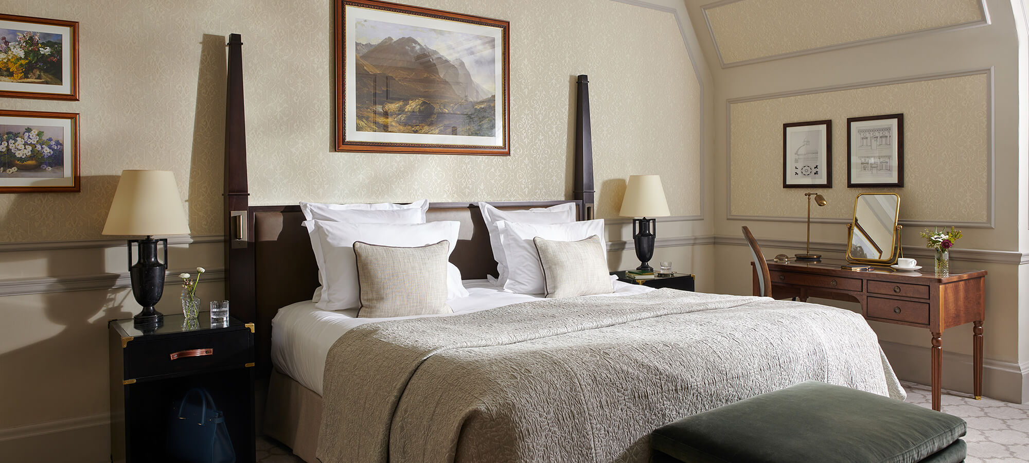 Un lit king-size dans une belle chambre Country avec des tableaux aux murs et un bureau à côté.