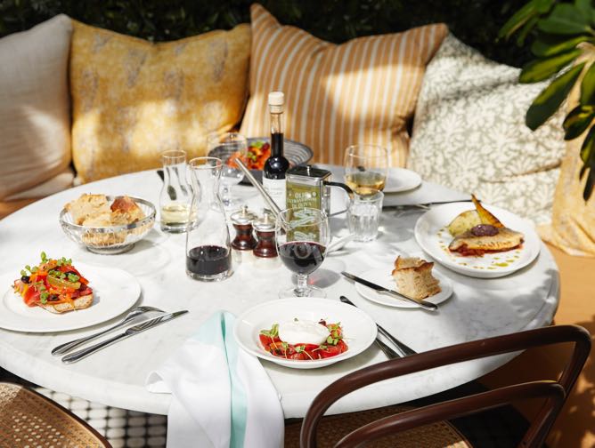 A white marble table top with a selection of brasserie favourites surrounded by a bay seat covered in yellow cushions