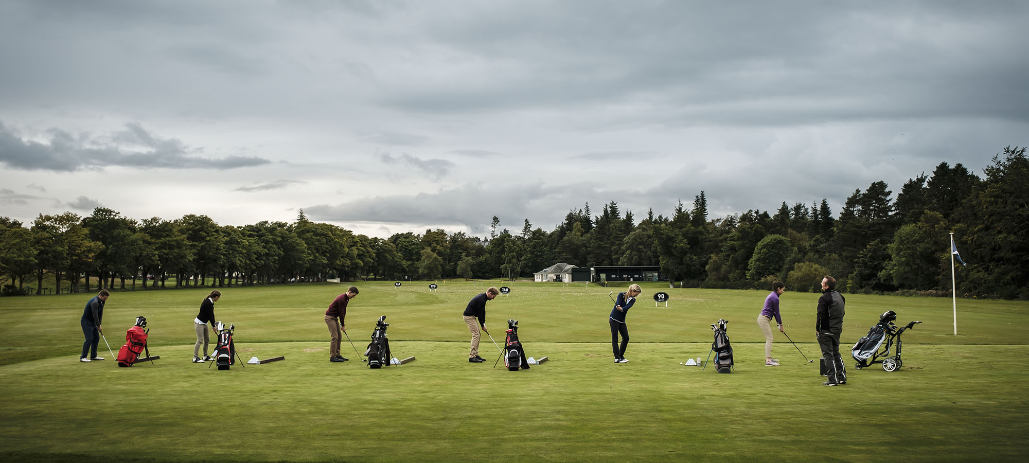 A group of golfers hit balls on a driving range