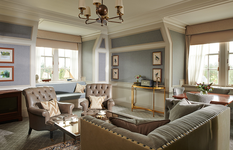 A sitting room in a suite with duck egg blue walls and grey leather chairs