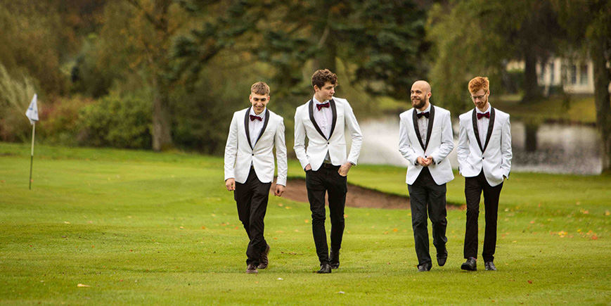 4 men in white dinner jackets and bow ties on a golf course at Gleneagles