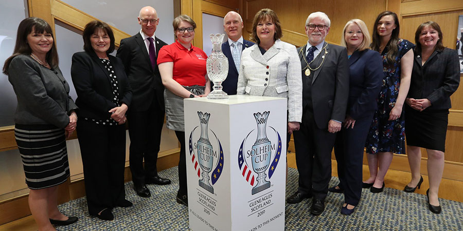 A group of officials and dignitaries standing around the Solheim Cup