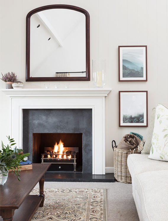 A large white living room with roaring open fire