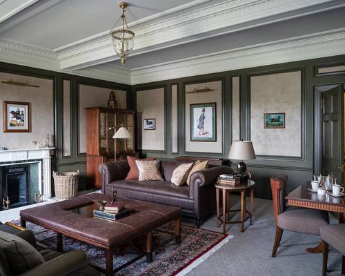 Dark grey leather sofa and ottoman in a dark green painted living room