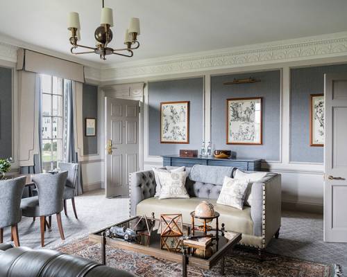 A large, blue sitting room with leather sofas and antiques on the coffee table