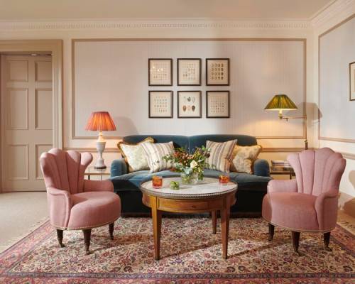A sitting room on a whisky suite at Gleneagles with pink arm chairs and a large green sofa