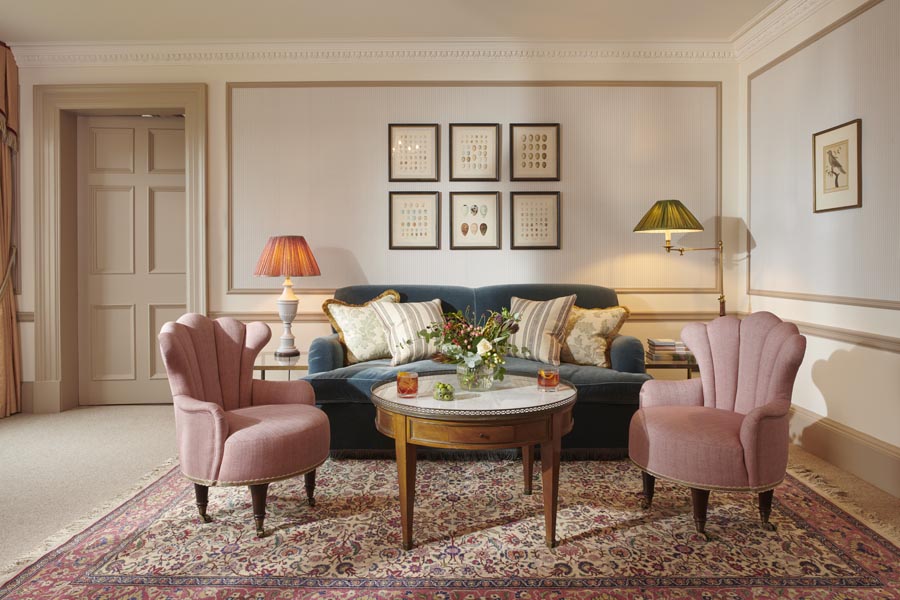 A sitting room on a whisky suite at Gleneagles with pink arm chairs and a large green sofa