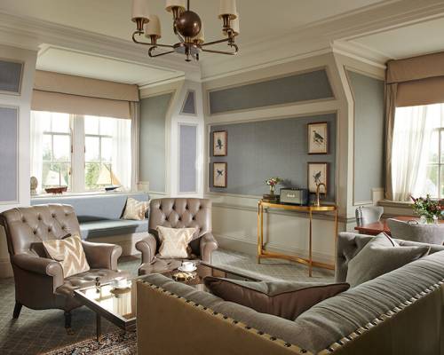 A large living room with grey leather sofa and armchairs around a glass table