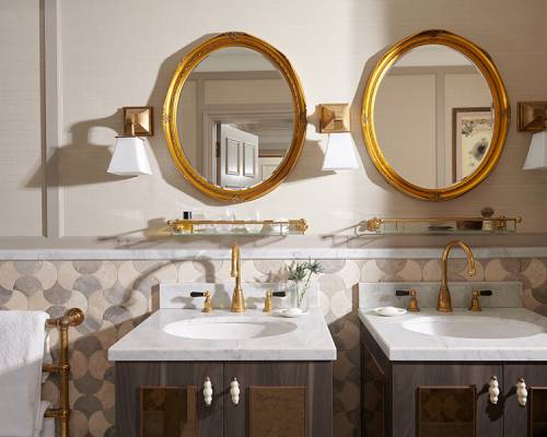 Twin marble vanity sinks with matching gold wall mirrors
