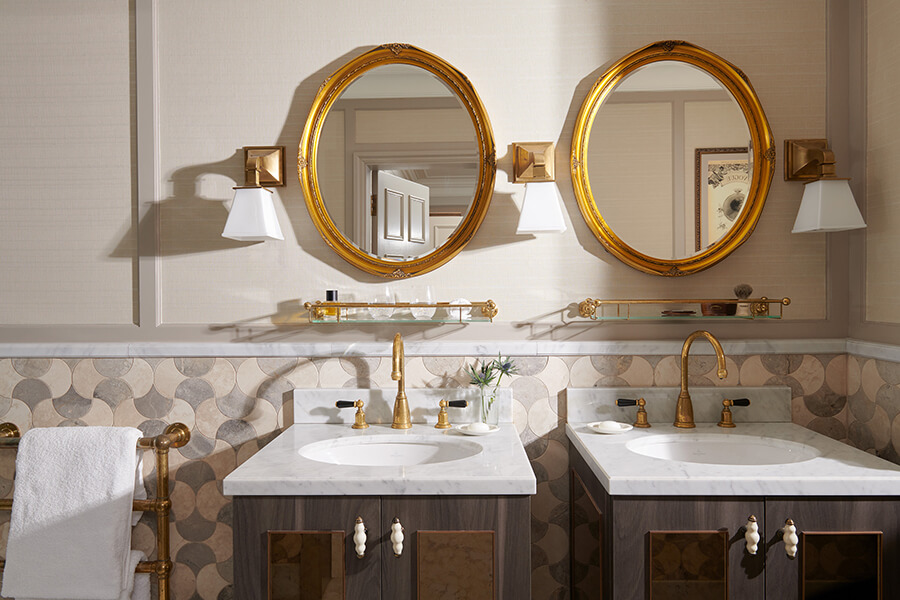 Twin marble vanity sinks with matching gold wall mirrors