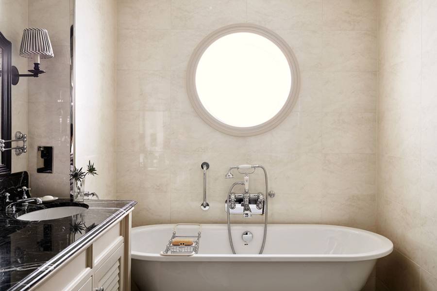 A large roll top bath with large circular window above it in a Braid Estate Bedroom's bathroom