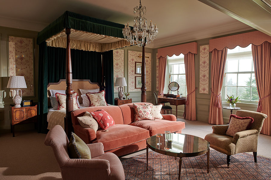 A grand four-poster bed sits in the middle of the Royal Lochnagar Suite bedroom with seating area
