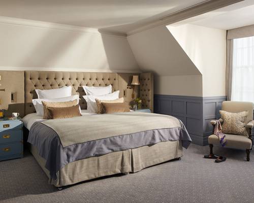 A king sized bed in a brightly lit large bedroom