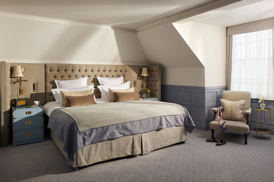 A king sized bed in a brightly lit large bedroom