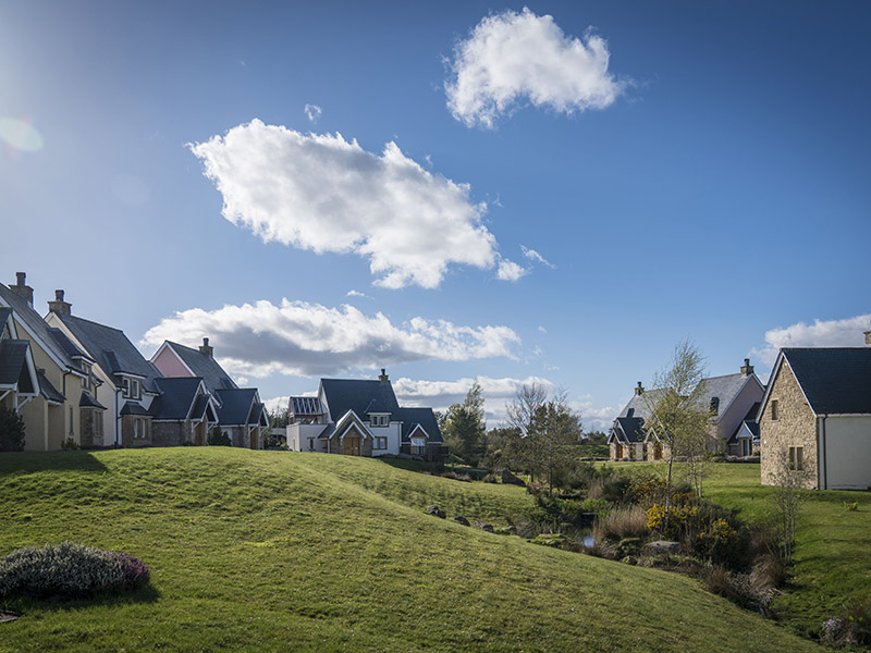 A wide open grassy area between houses on a bright and sunny day
