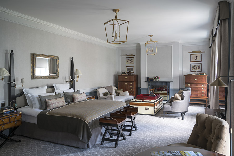 A very large Manor room with a seating space featuring grey chairs and chest ottoman