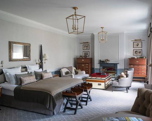 A very large Manor room with a seating space featuring grey chairs and chest ottoman