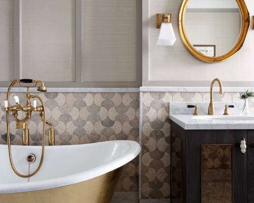A gold rolltop bath, marble sink and gold wall mirror
