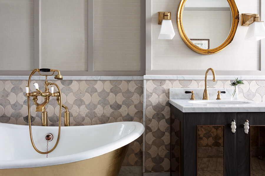 A gold rolltop bath, marble sink and gold wall mirror