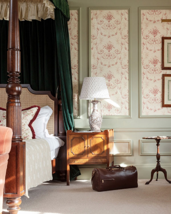 A brown leather day bag sits next to a side table of a luxury four poster bed at Gleneagles 5 star resort