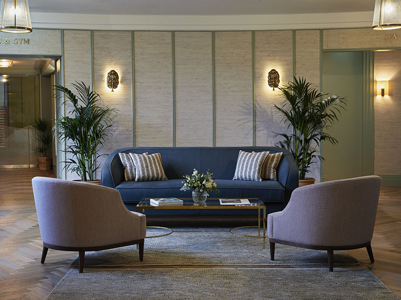 A blue sofa and pink bucket chairs in the seating area in a health club