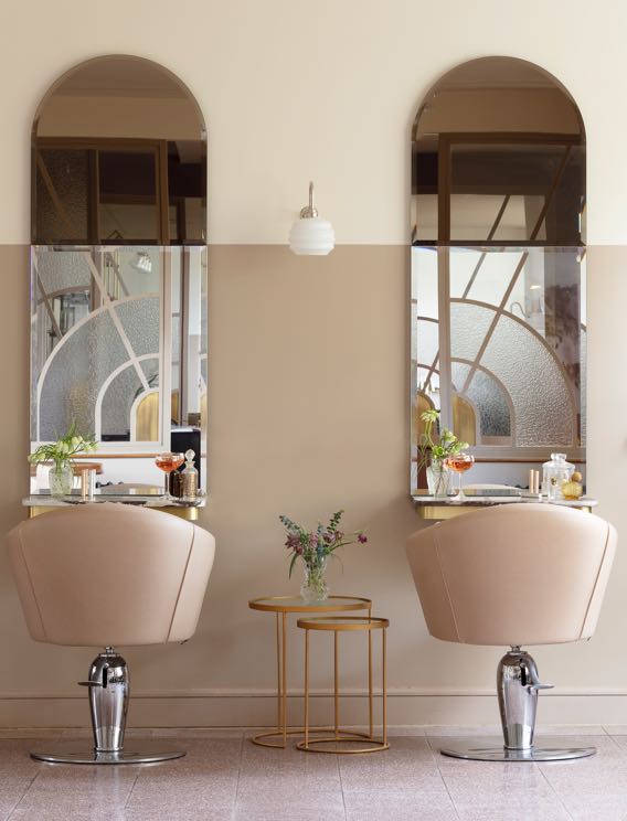 Two light pink leather hairdressing chairs in front of mirrors in the art deco salon