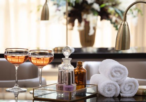 Two glasses of rose champagne alongside nail polish and manicure towels