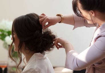 A stylist pinning up a brunettes hair