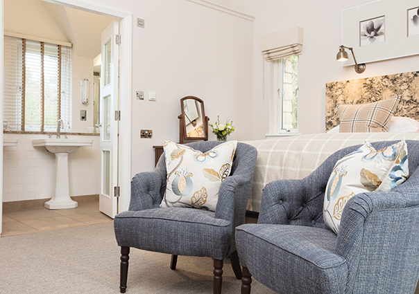 Two large blue armchairs at the foot of a bed