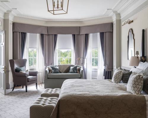 A large Estate bedroom with bay window, king sized bed and ample seating