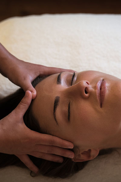 A spa therapists hands massaging a woman's face