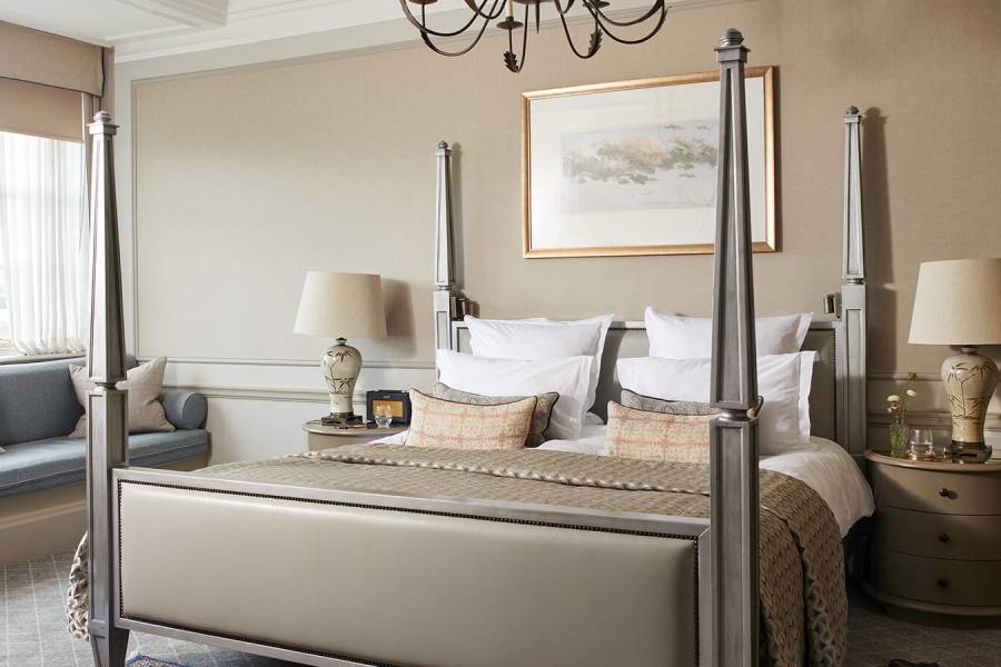 A large four-poster bed in a beige coloured room in an estate suite