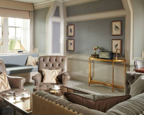 A large sitting room in a suite with two grey leather Chesterfield chairs in an estate suite