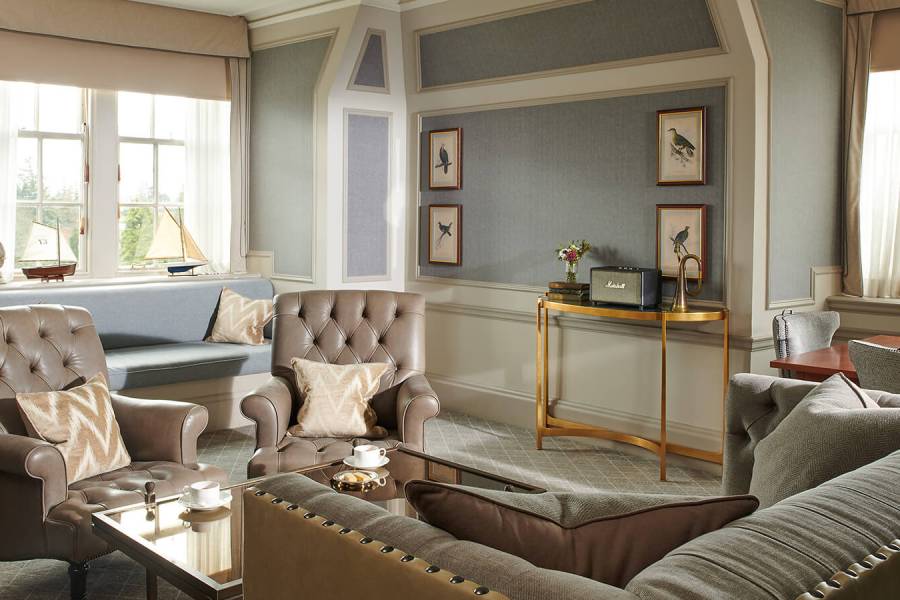 A large sitting room in a suite with two grey leather Chesterfield chairs in an estate suite