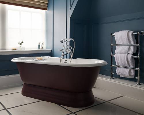 A large plum coloured free-standing bathtub in a navy blue bathroom in a Manor room