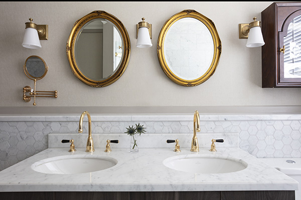A white marble double vanity sink and gold double mirrors