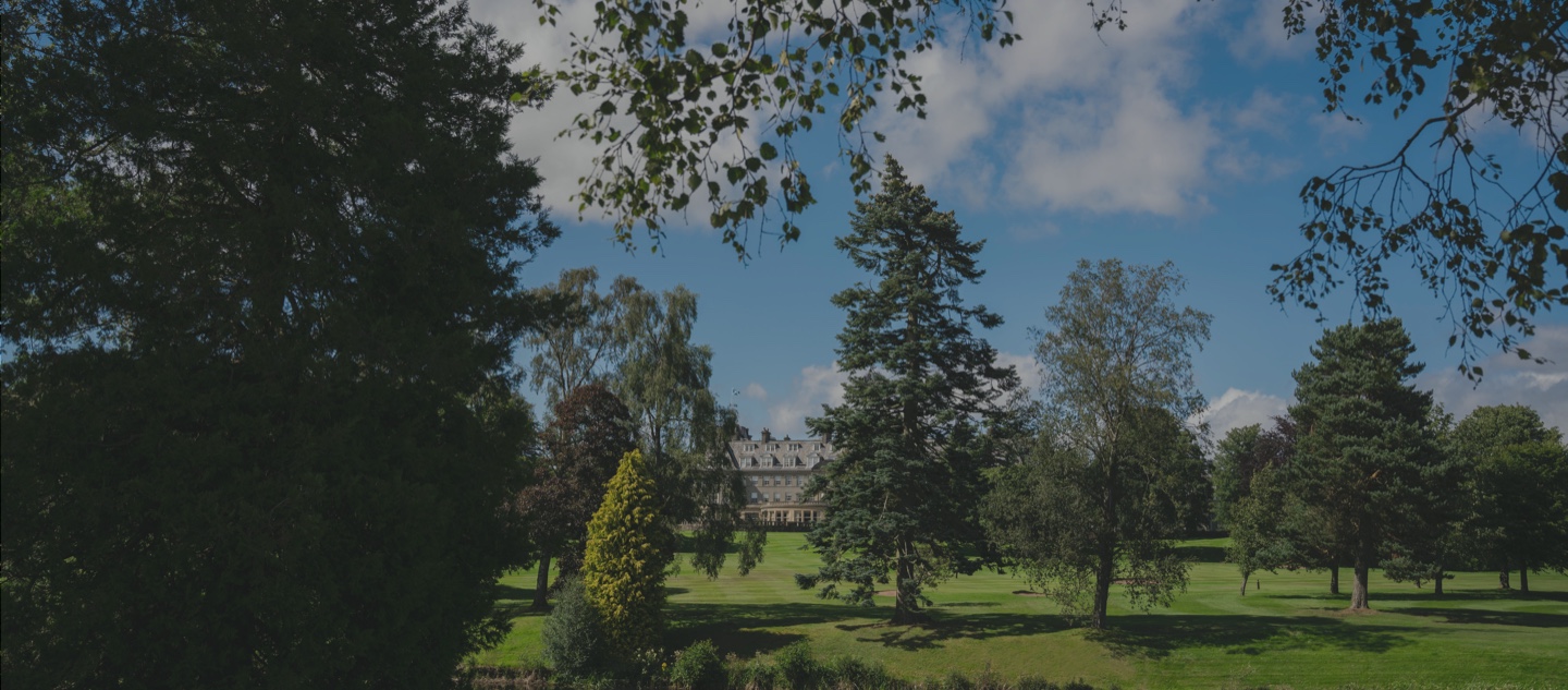 A view of the Gleneagles hotel through trees on the estate grounds