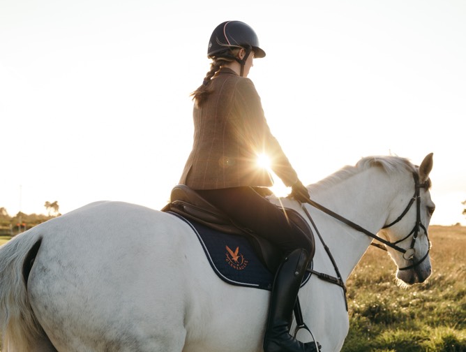 A woman riding a grey horse at sunset at Gleneagles