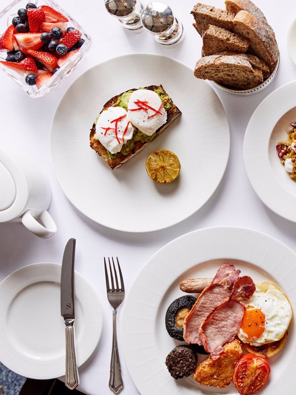 Poached egg and avocado, full Scottish breakfast, a berry fruit salad and toast on a table