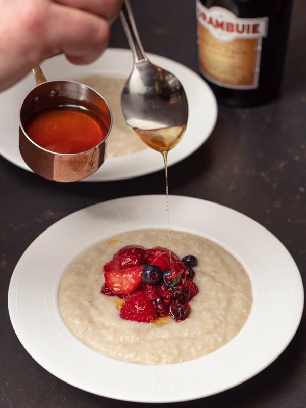 Porridge with berries and a chef bring syrup from a spoon on it