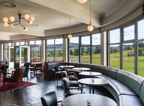 Leather seating and dark wooden table sit in front of large window s with views to the Kings and Queens golf courses