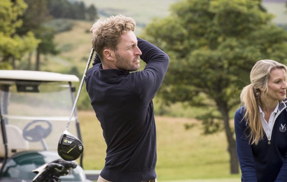 A man finishing his swing on a driving range