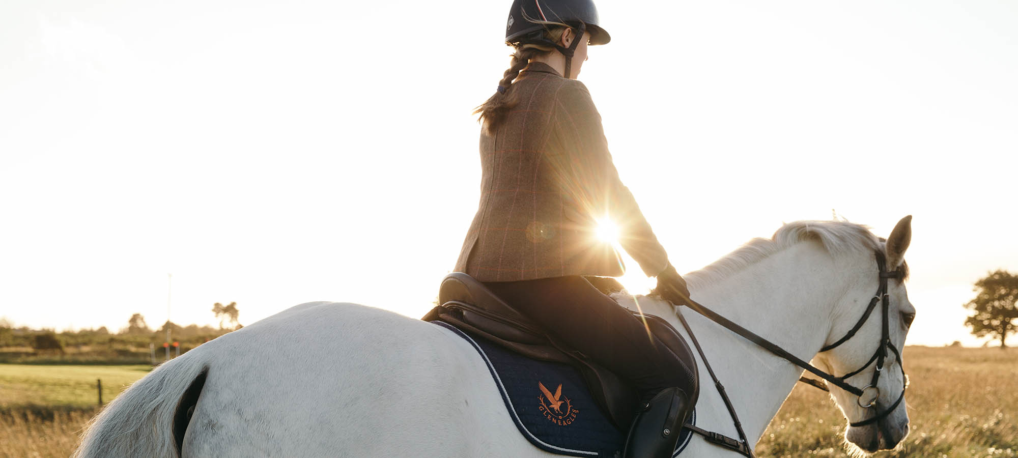 A woman on a horse rides into the sunset at Gleneagles Scottish Equestrian centre
