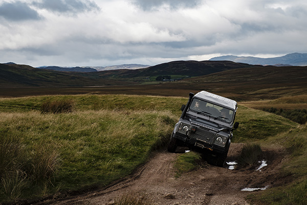 A land rover defender makes its way a long a track surrounded by the hills and heather of highland Perthshire during an off-road lesson