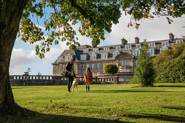 A girl and her older sister walk a dog through the ground sofa Gleneagles on an autumn day