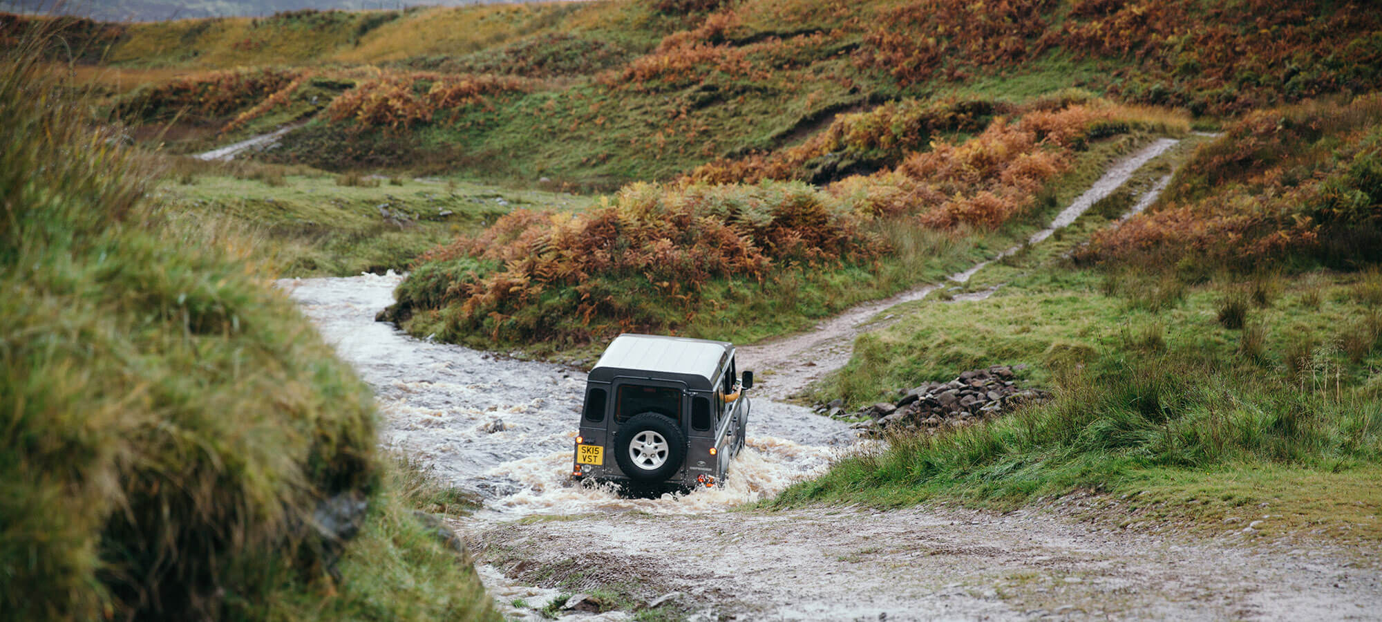 A Land Rover defender drives through a river deep in the Scottish countryside
